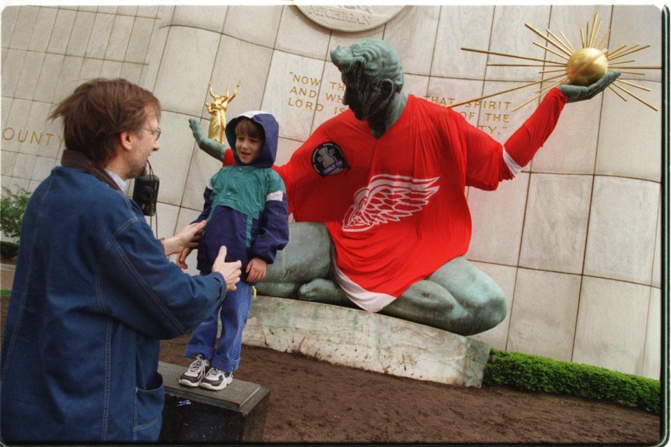 Alan Jacquemotte positions his son Alan, 4, of Warren, for a photo in front of a Red Wings clad Spirit of Detroit in 1997.