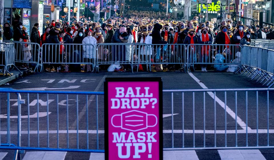 A sign reminds people to wear face masks as revelers gather on Times Square in New York Friday, Dec. 31, 2021 for New Year's Eve celebrations.