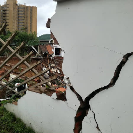 Vehicles and debris that have been washed away after massive flooding are seen behind a damaged building in Amanzimtoti, near Durban, South Africa April 23, 2019 in this picture obtained from social media on April 24, 2019. Gavin Welsh via REUTERS