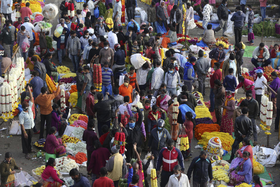 Shoppers crowd at a wholesale flower market in Bengaluru, India, Friday, Nov. 20, 2020. India's total number of coronavirus cases since the pandemic began has crossed 9 million. Nevertheless the country's new daily cases have seen a steady decline for weeks now. (AP Photo/Aijaz Rahi)