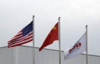 The company flag of OSI (R), and U.S. and Chinese national flags flutter in front of OSI's food processing plants in Langfang, Hebei province, July 23, 2014. REUTERS/Paul Carsten