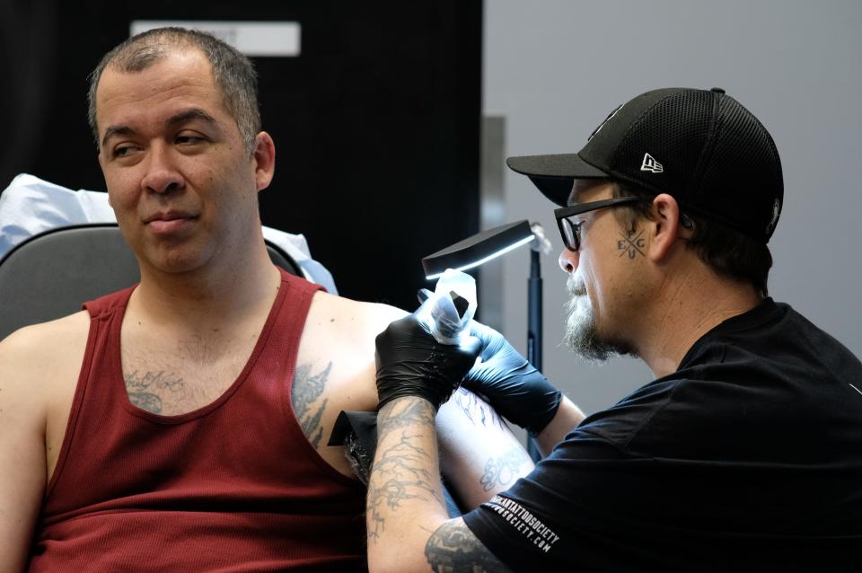 Command Sgt. Maj. Gregory Seymour gets a tattoo by Billy Bowermaster during the Dec. 19, 2023, grand opening of American Tattoo Society on Fort Liberty.