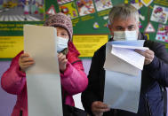 People examine their ballots during the State Duma, the Lower House of the Russian Parliament and local parliament elections at a polling station in St. Petersburg, Russia, Sunday, Sept. 19, 2021. The head of Russia's Communist Party, the country's second-largest political party, is alleging widespread violations in the election for a new national parliament in which his party is widely expected to gain seats. (AP Photo/Dmitri Lovetsky)