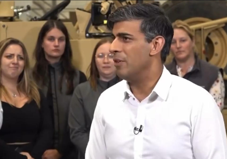 The woman, seen left in the picture, appeared to look puzzled and grimaced as Rishi Sunak made his speech. (X)