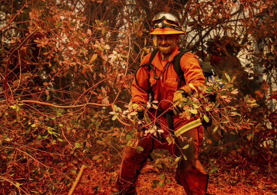 An inmate firefighter clears brush while battling the Fawn Fire burning north of Redding in Shasta County, Calif., on Thursday, Sept. 23, 2021. (AP Photo/Ethan Swope)