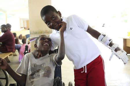 Handicapped Haitian boy Stevenson Joseph (R), wears the 3D-printed prosthetic hand that he is learning to use while posing with a friend at the orphanage where he lives in Santo, near Port-au-Prince, April 28, 2014. REUTERS/Marie Arago