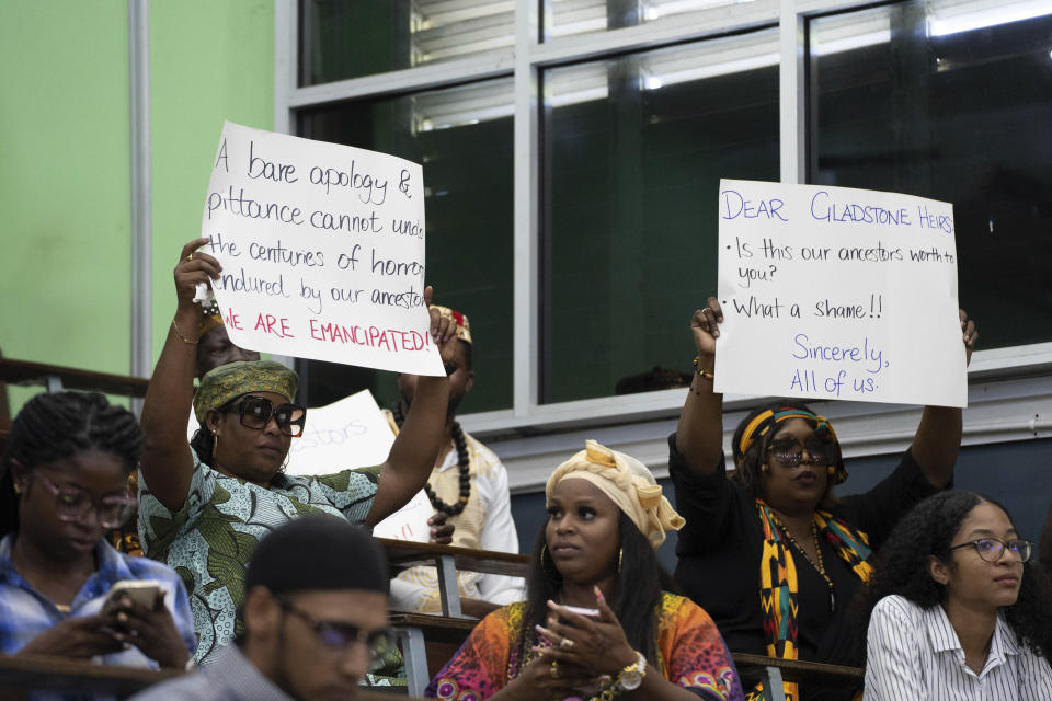 People hold up messages during a speech by Charles Gladstone, a descendant of former plantation owner John Gladstone, as he delivers an apology on behalf of the Gladstone family at Georgetown University in Georgetown, Guyana, Friday, Aug. 25, 2023. The descendants of a 19th-century Scottish sugar and coffee planter who owned thousands of slaves in Guyana apologized Friday for the sins of their ancestor, calling slavery a crime against humanity with lasting negative impacts. (AP Photo/Chris Leung)