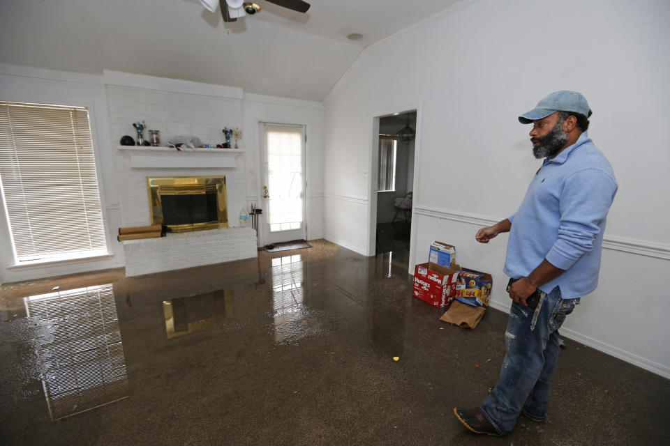 Marcus Morris inspects his girlfriend's house in Jackson, Miss., as Pearl River flood water is reflected on the living room floor, Sunday, Feb. 16, 2020. Residents of Jackson braced for the possibility of catastrophic flooding in and around the Mississippi capital as the Pearl River rose precipitously after days of torrential rain. (AP Photo/Rogelio V. Solis)