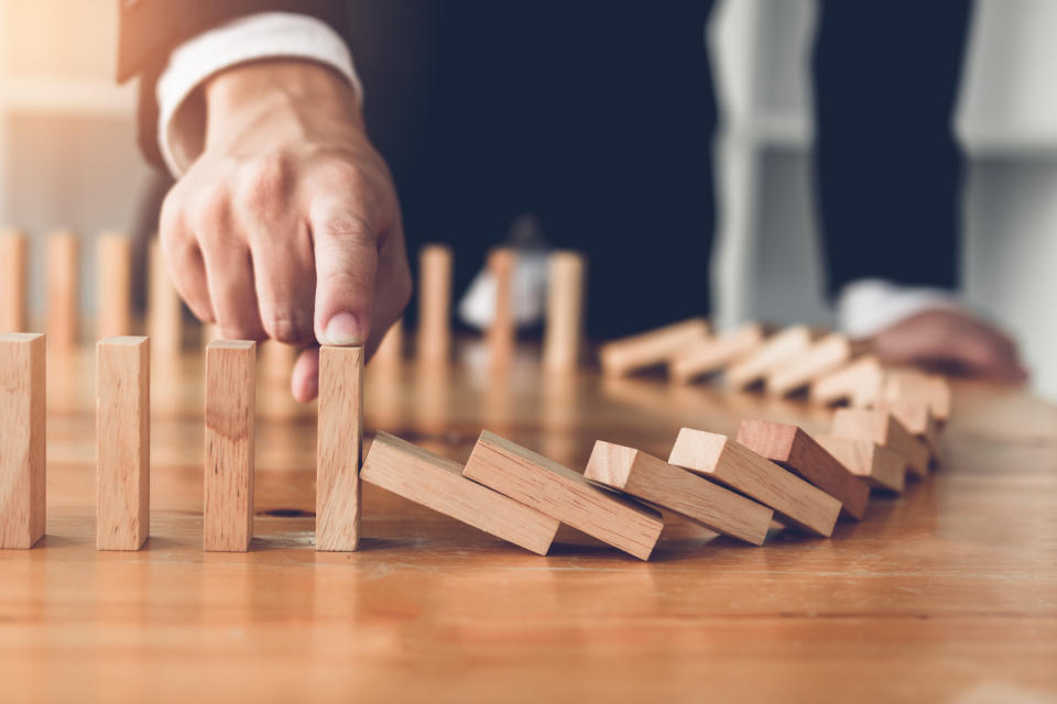 A businessman knocks down wooden dominoes.