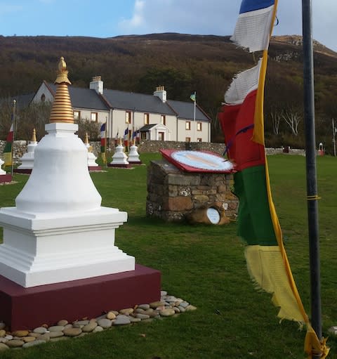 The Tibetan prayer flags and eight white ornamental ‘stupas’ (symbolising the enlightened mind of the Buddha) lead the way up to the retreat centre - Credit: Anna Turns