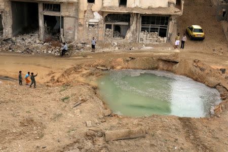 People inspect a hole in the ground filled with water in a damaged site after airstrikes on the rebel held Tariq al-Bab neighborhood of Aleppo, Syria. REUTERS/Abdalrhman Ismail