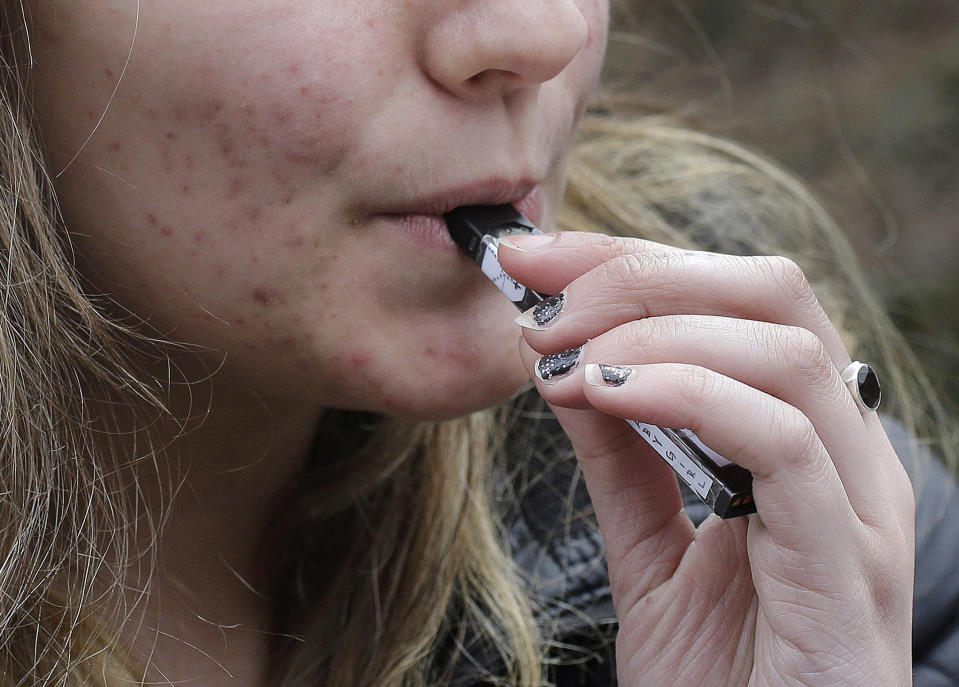 FILE - In this April 11, 2018, file photo, a high school student uses a vaping device near a school campus in Cambridge, Mass. California Gov. Gavin Newsom will announce an executive action Monday, Sept. 16, 2019, to confront youth heath concerns related to vaping. (AP Photo/Steven Senne, File)