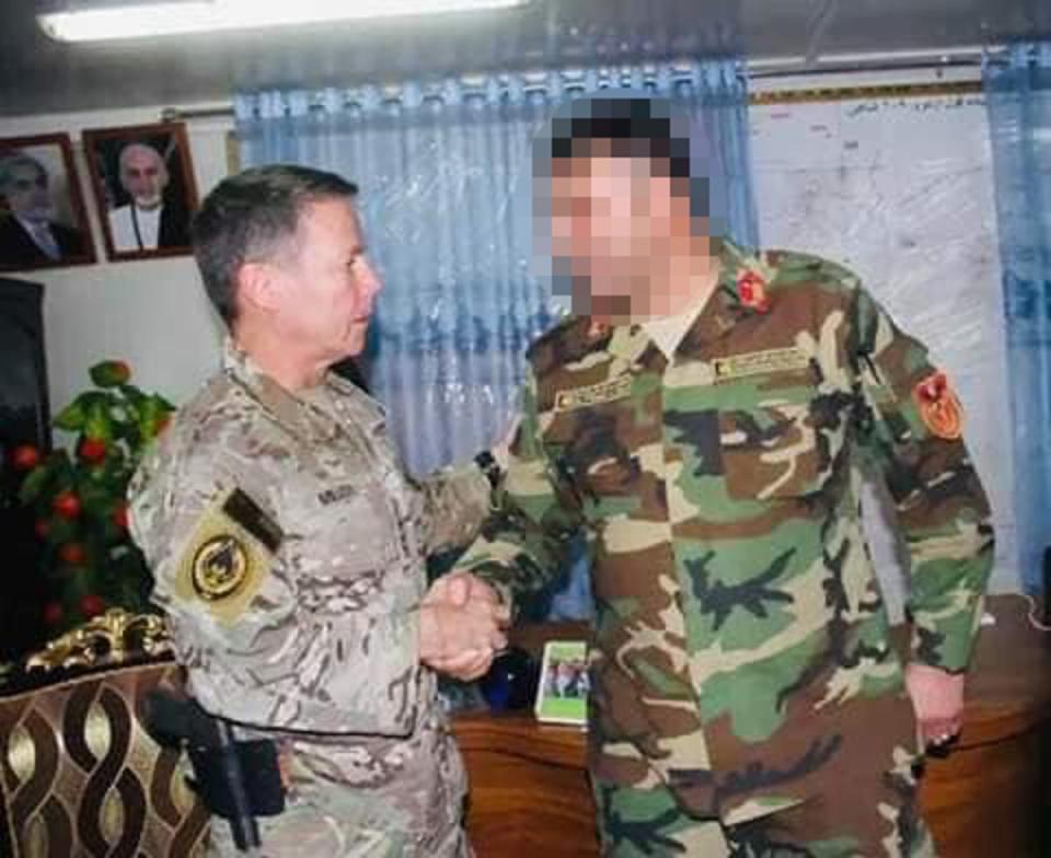 An Afghan colonel, pictured here shaking hands with four-star US general Austin Scott Miller, was threatened with deportation to Rwanda after he came to the UK via small boat (Supplied)