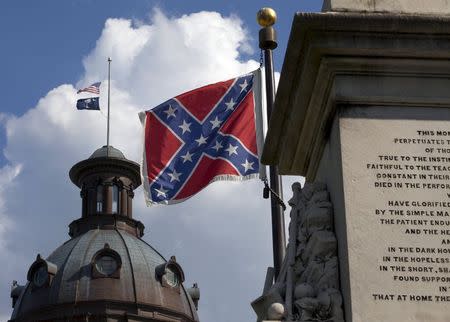 The U.S. flag and South Carolina state flag flies at half staff to honor the nine people killed in the Charleston murders as the confederate battle flag also flies on the grounds of the South Carolina State House in Columbia, SC June 20, 2015. REUTERS/Jason Miczek