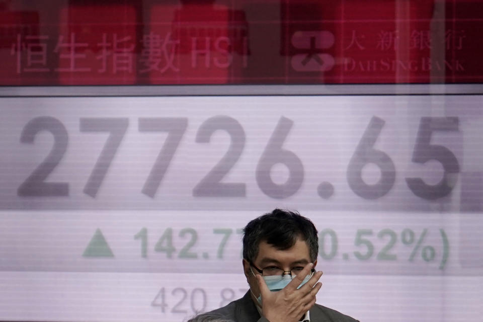 A man walks past an electronic board showing Hong Kong share index outside a local bank in Hong Kong, Wednesday, Feb. 12, 2020. Asian shares were higher Wednesday, although the outbreak of a new virus in the region continued to weigh on investor sentiments. (AP Photo/Kin Cheung)