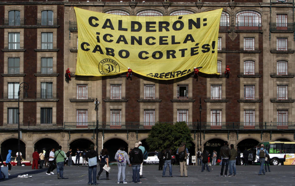 Greenpeace activists hang a banner from a building in front of the Zocalo, Mexico City's main plaza,Tuesday March 27, 2012. Greenpeace is protesting plans to build a resort in Cabo Pulmo on the Baja California peninsula. The banner reads in Spanish; "Calderon: Cancel Cabo Cortes," the commercial name of the planned resort. (AP Photo/Marco Ugarte)