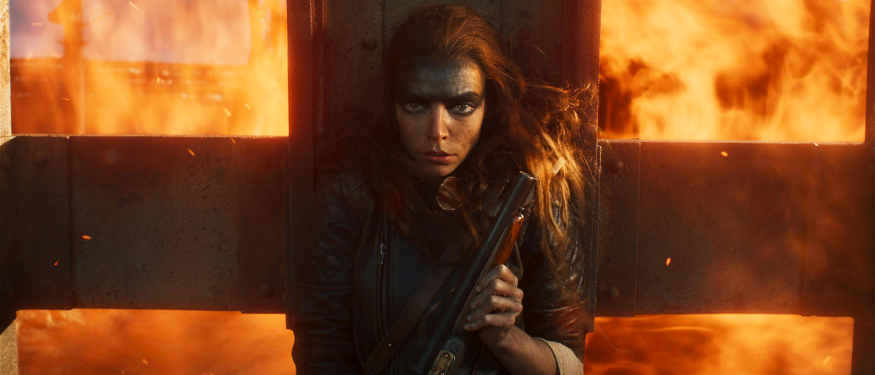  Anya Taylor-Joy takes cover with a shotgun as flames engulf the background in Furiosa: A Mad Max Saga. . 