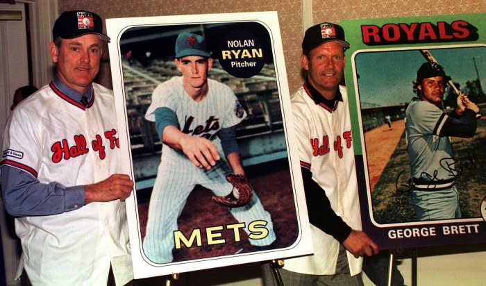 Newly elected Baseball Hall of Fame inductees pitcher Nolan Ryan and outfielder George Brett pose with their respective baseball cards January 6, 1999. File Photo by Ezio Petersen/UPI
