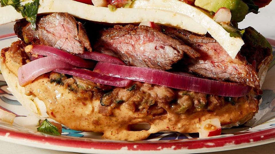 the carne asada torta is assembled with tenera bread, refried beans, sliced marinated steak, pickled onions, avocado radish relish and queso fresco
