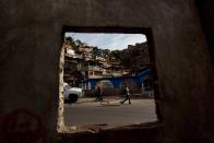 In this March 27, 2014 photo, residents walk in the Petare shanty town in Caracas, Venezuela. For supporters of President Nicolas Maduro's government, Cuban doctors are an example of concrete improvements in their lives delivered under the late President Hugo Chavez and now his hand-picked successor. (AP Photo/Fernando Llano)