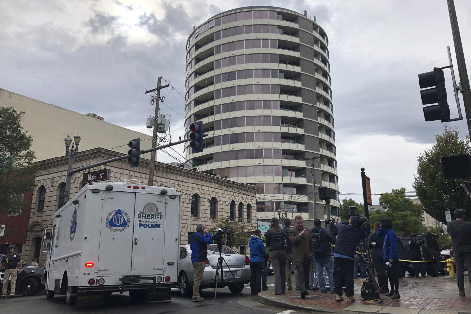 Police respond to a shooting at an apartment building, top rear, in Vancouver, Wash., Thursday, Oct. 3, 2019. Vancouver police say a resident of the building shot several people in the lobby of the Smith Tower Apartments. (AP Photo/Gillian Flaccus)