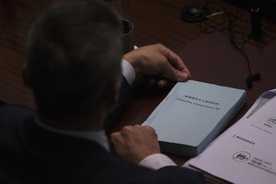 A lawmaker holds a copy of the proposed Safeguarding National Security Bill during the second reading of the Basic Law Article 23 legislation at the Legislative Council in Hong Kong, Tuesday, March 19, 2024. (AP Photo/Louise Delmotte)