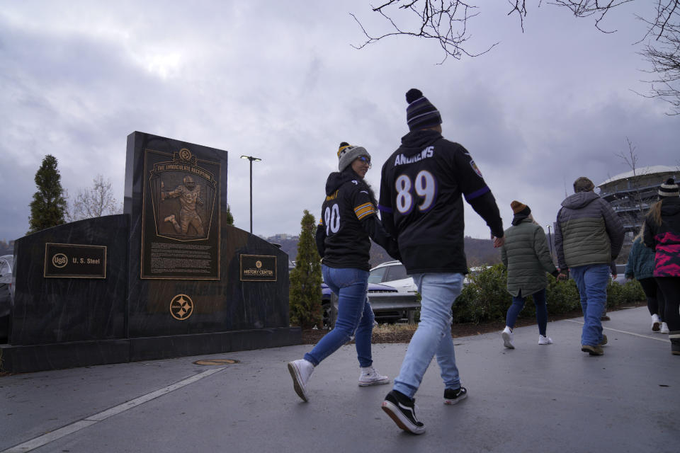 Pittsburgh Steelers fans walk past a marker commemorating the exact spot where the 1972 "Immaculate Reception," was made by Franco Harris at Three Rivers Stadium, which once stood on the North Side of Pittsburgh, on Sunday, Dec. 11, 2022, in Pittsburgh, Pa. Harris' scoop of a deflected pass and subsequent run for the winning touchdown in a 1972 playoff victory against Oakland has been voted the greatest play in NFL history and celebrates its 50th anniversary this year. (AP Photo/Jessie Wardarski)