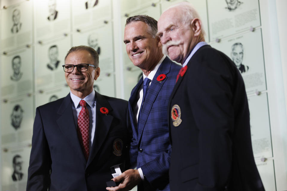 Hockey Hall of Fame 2023 inductee Pierre Turgeon, center, receives his Hockey Hall of Fame ring from Mike Gartner, left, and Lanny McDonald as he's inducted into the Hall in Toronto Friday, Nov. 10, 2023. (Cole Burston/The Canadian Press via AP)