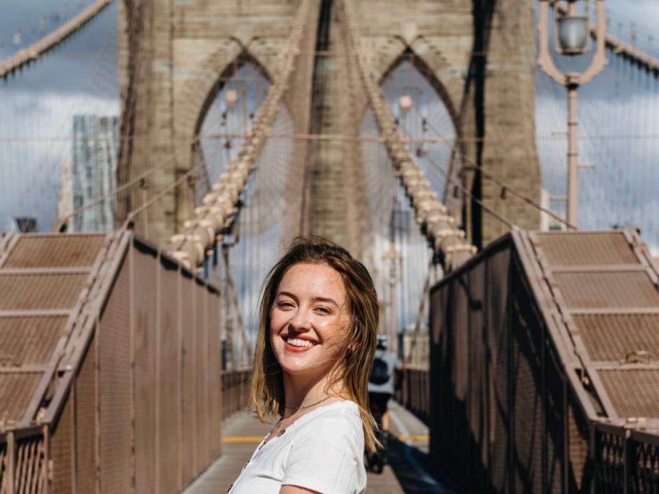 The writer stands in front of a bridge in New York City