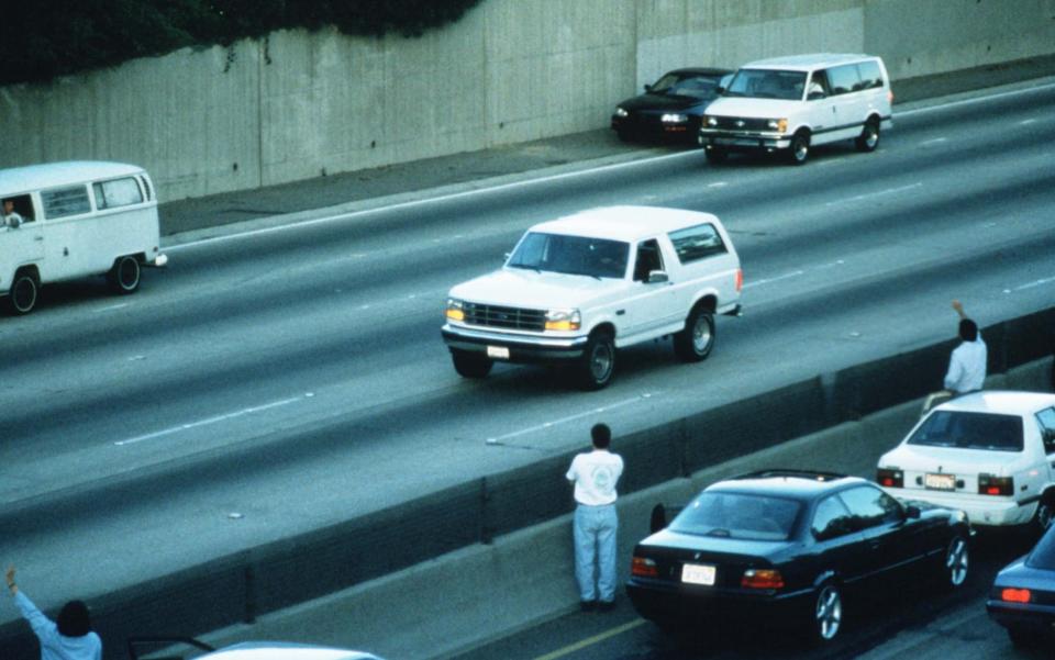 Al Cowlings drives football star O.J. Simpson south on LA Highway 405 in a white Ford Bronco followed by police cars June 17, 1994 in Los Angeles, CA -  Jean-Marc Giboux/Getty Images