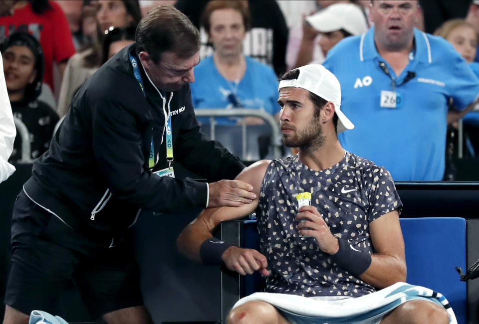 Russia's Karen Khachanov receives treatment from a trainer during his third round singles match Australia's Nick Kyrgios at the Australian Open tennis championship in Melbourne, Australia, Saturday, Jan. 25, 2020. (AP Photo/Lee Jin-man)