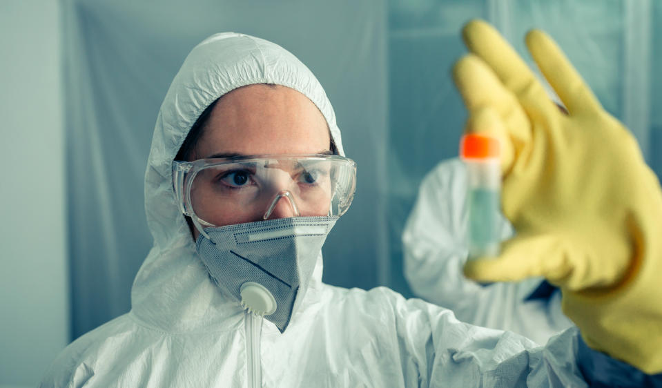 Female doctor looking at vial with vaccine for virus treatment