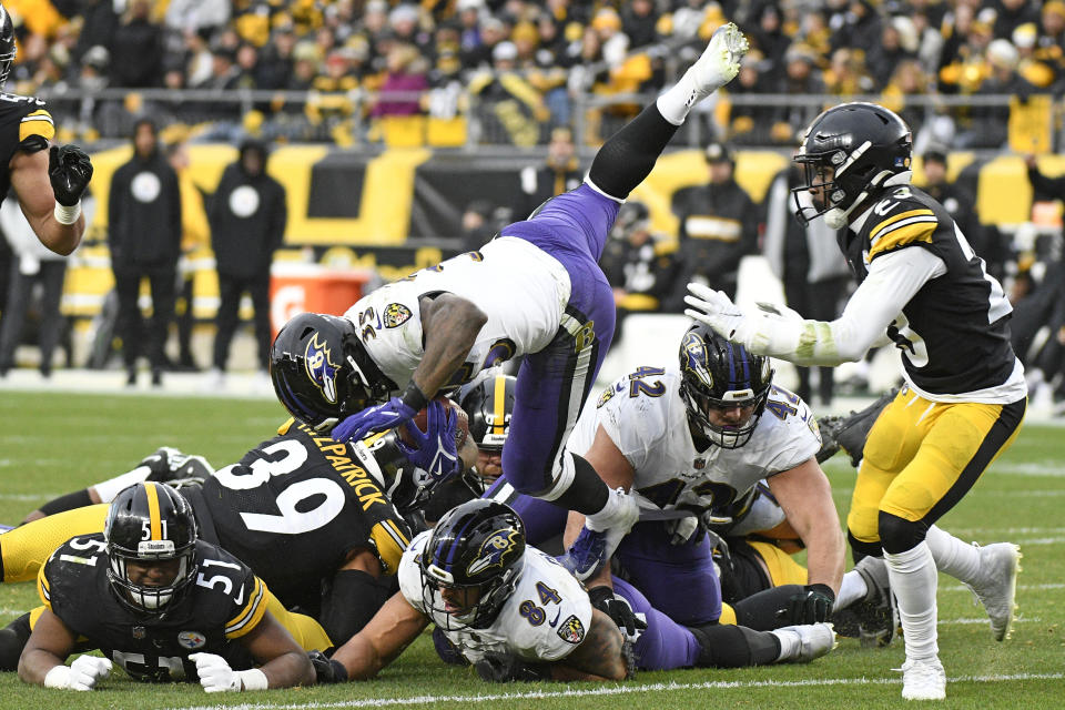 Baltimore Ravens running back Gus Edwards leaps over the pile during the second half of an NFL football game against the Pittsburgh Steelers in Pittsburgh, Sunday, Dec. 11, 2022. (AP Photo/Don Wright)