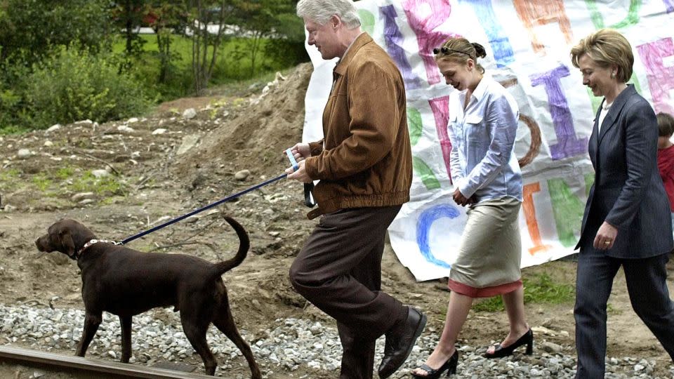 Former President Bill Clinton holding onto his dog Buddy with then first lady Hillary Clinton and their daughter Chelsea during their vacation in Saranac Lake, New York in August 2000. - Joyce Naltchayan/AFP/Getty Images