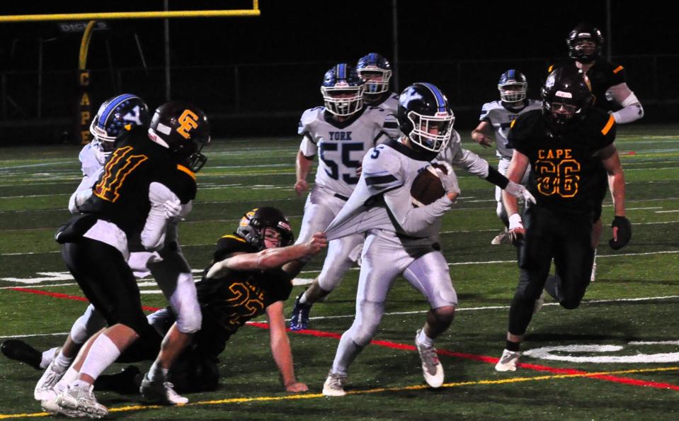 York’s Brody Gullison, center, tries to shake off Cape’s Mike Foley during Monday night’s Class C South playoff game in Cape Elizabeth, Maine. York lost 41-6 and ended its season with a record of 2-7.