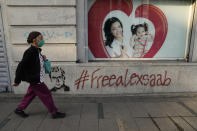 A pedestrians walks past a graffiti asking for the freedom of Colombian businessman and Venezuelan special envoy Alex Saab, in Caracas, Venezuela. Saturday, Oct. 16, 2021. Saab, a top fugitive close to Venezuela's socialist government has been put on a plane from Cape Verde to the U.S. to face money laundering charges, a senior U.S. official confirmed Saturday. 2021. (AP Photo/Ariana Cubillos)