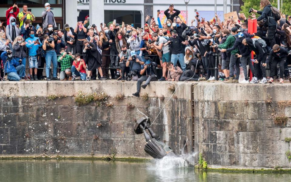 The statue of 17th century slave trader Edward Colston falls into the water after protesters pulled it down and pushed into the docks in Bristol - KEIR GRAVIL via REUTERS 