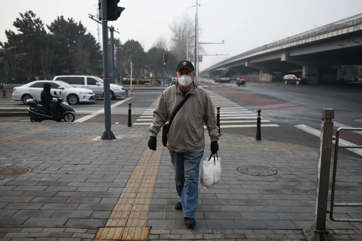 A man wears a face mask as he walks on a sidewalk in Beijing on February 13, 2020. - The number of deaths and new cases from China's COVID-19 coronavirus outbreak spiked dramatically on February 13 after authorities changed the way they count infections in a move that will likely fuel speculation that the severity of the outbreak has been under-reported. (Photo by GREG BAKER / AFP) (Photo by GREG BAKER/AFP via Getty Images)