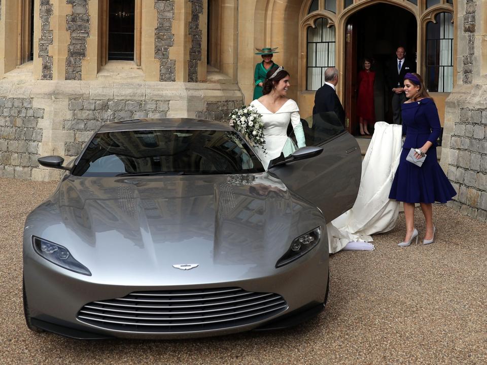 Princess Beatrice holds Princess Eugenie's wedding dress as she gets into a car on her wedding day in 2018.