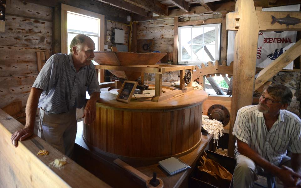 Head miller Doug Erickson, left, chats with apprentice Scott Leonard July 23 as the millstones start to turn grinding corn at the Brewster Grist Mill.