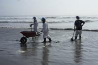 Workers clean up an oil spill at Cavero beach in Ventanilla, Callao, Peru, Monday, Jan. 17, 2022. Unusual high waves that authorities attribute to the eruption of the undersea volcano in Tonga caused the spill on the Peruvian Pacific coast as a ship was loading oil into La Pampilla refinery on Sunday. (AP Photo/Martin Mejia)