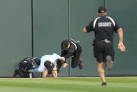 A baseball fan is subdued by security guards after trying to climb the left center wall after running on the field at the start of a baseball game between the Chicago White Sox and the Tampa Bay Rays, Saturday, April 27, 2024, in Chicago. (AP Photo/Charles Rex Arbogast)