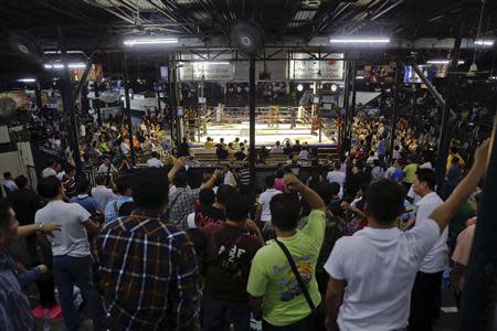 Spectators follow a fight during the closing Thai boxing, or "Muay Thai", fight night of the legendary Lumpinee stadium, one of Bangkok's oldest boxing venues which is being demolished after 57 years, February 7, 2014. REUTERS/Damir Sagolj