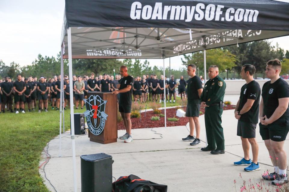 Dennis Castellanos, command chief warrant officer of the 7th Special Forces Group, addresses a crowd of more than 1,000 people taking part in the annual 9/11 Memorial Run on Friday.