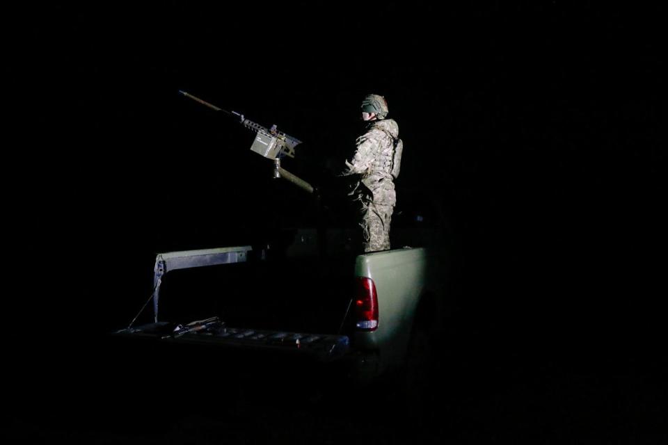 Ukraine's 117th Territorial Defense Brigade soldier watching the sky while standing on a pickup truck mounted a heavy machine gun in Sumy Oblast, Ukraine as Russia launched dozens of Shahed kamikaze drones in late March 2024. (Alexander Khrebet / The Kyiv Independent)