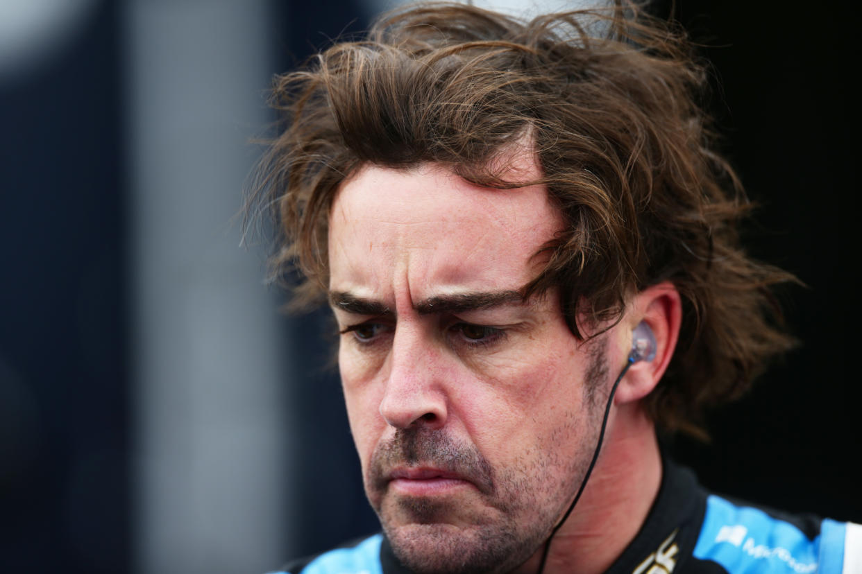 Fernando Alonso, con mirada seria y pensativa y unos auriculares puestos.