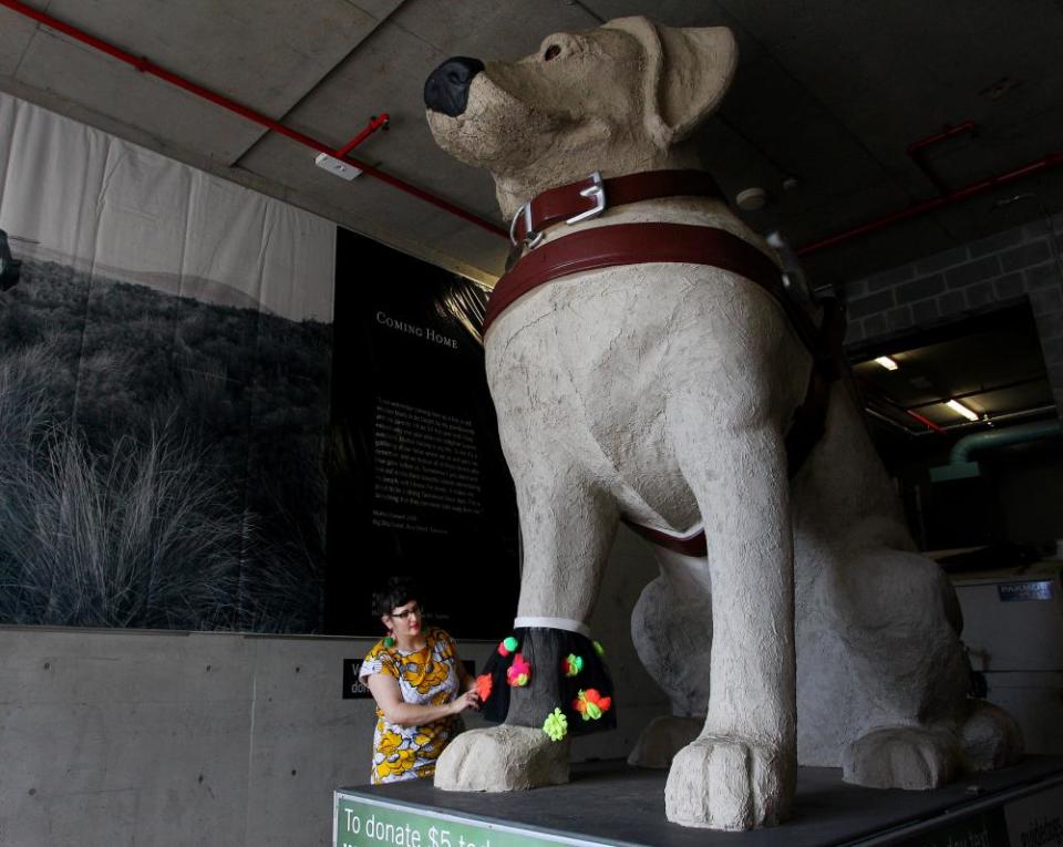 Nicole Barakat, Artist Educator at the MCA puts a textural ruffle around the paw of Gulliver, a giant guide dog statue.