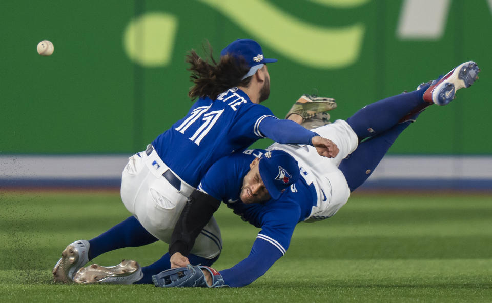 Toronto Blue Jays shortstop Bo Bichette (11) and Toronto Blue Jays center fielder George Springer collide while trying to catch a short fly ball during the eighth inning of Game 2 of a baseball AL wild-card playoff series Saturday, Oct. 8, 2022, in Toronto. (Frank Gunn/The Canadian Press via AP)