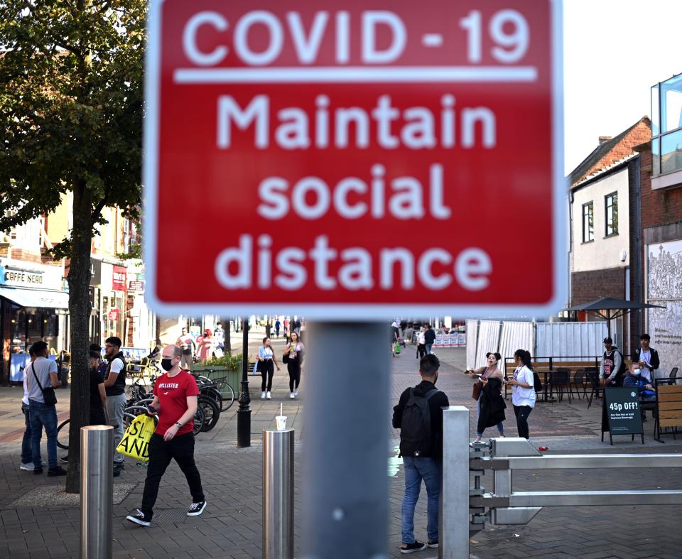 People walk past a sign encouraging social distance in a shopping street in Solihull, central England on September 14, 2020 after the British government imposed fresh restrictions on the area after a rise in cases of the novel coronavirus. - Authorities in Britain's second city of Birmingham announced new coronavirus restrictions Friday as the nation's viral reproduction rate, or R number, exceeded 1.0 for the first time since March. (Photo by Oli SCARFF / AFP) (Photo by OLI SCARFF/AFP via Getty Images)