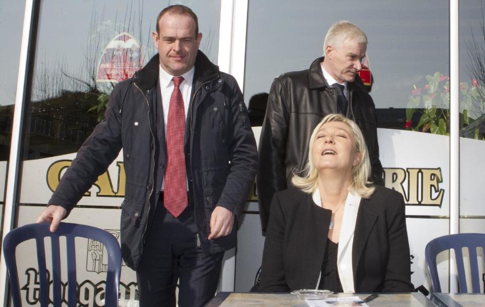 FILE - In this March 8, 2014 file photo, French far-right party leader Marine Le Pen, right, enjoys the sun, with Henin-Beaumont city candidate Steve Briois, left, and Carvin city candidate Alain Beghin ,right behind, in Carvin, near Henin-Beaumont, northern France, as part of the municipal campaign. Marine Le Pen sees political gold in the abandoned coal mines of northern France that once pumped life, jobs and an identity into places like Henin-Beaumont, a bleak town that the far-right leader says is the avant-garde of her anti-immigration party's march to power. (AP Photo/Jacques Brinon, File)